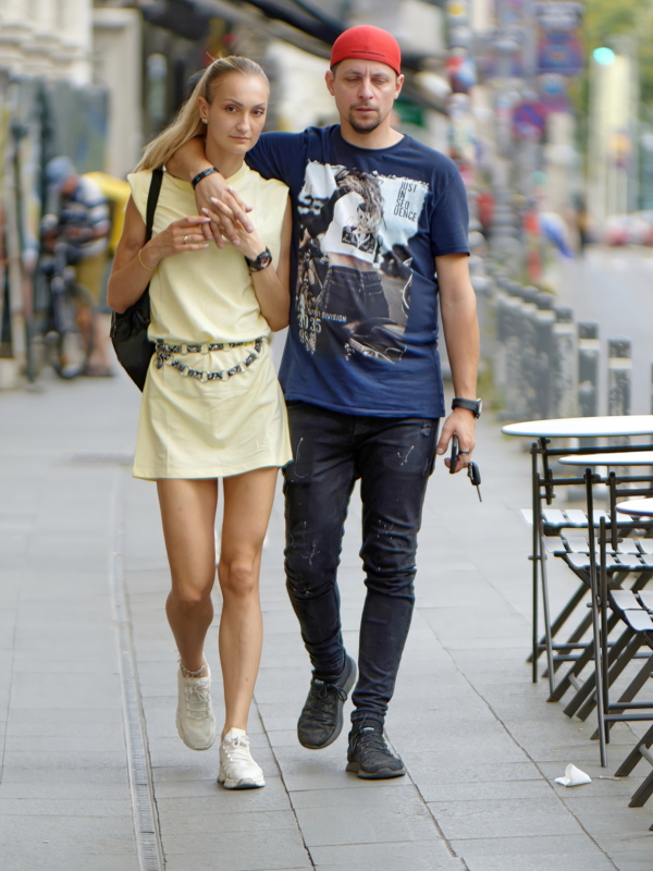 A couple walking together along a paved urban sidewalk